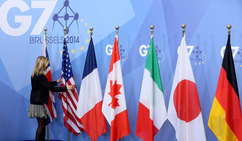 An official adjusts flags during the G7 summit